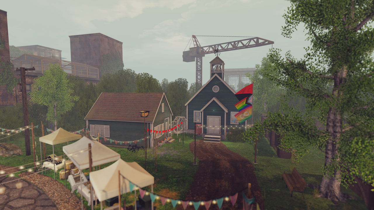 From a pair of canopy shelters in the foreground leads a short dirt road to a pair of small buildings, one of which in the style of a schoolhouse. A flagpole has the red & black anarchist flag, the pride progress flag, and an autism pride flag. A crane is in the background.