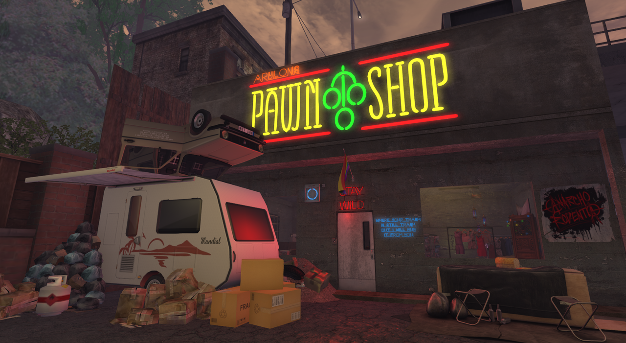 A building with a colorful neon sign. In front is a small camper trailer and various boxes.